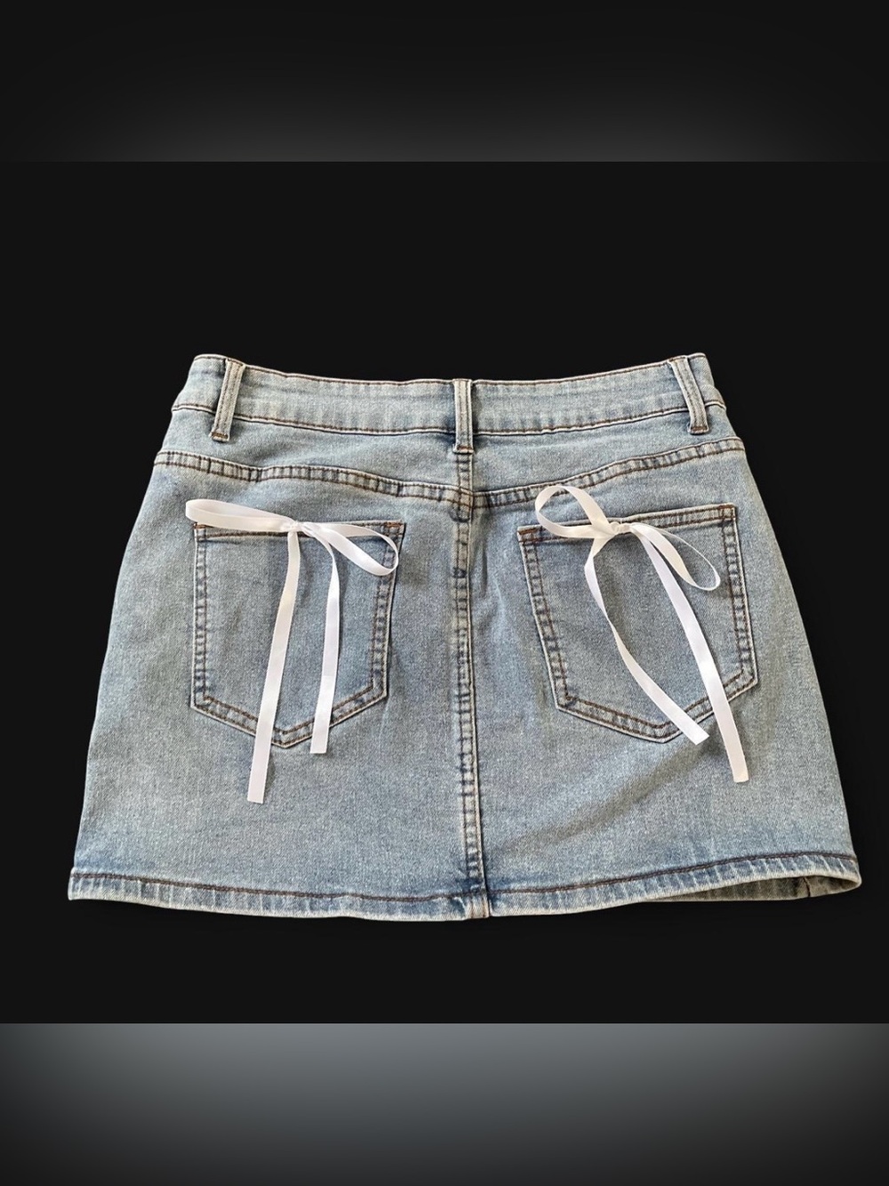 Blue denim mini skirt with white ribbon bows on back pockets